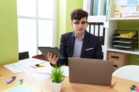 Téléchargez les photos : Homme non binaire travailleur d'affaires en utilisant touchpad et ordinateur portable au bureau - en image libre de droit
