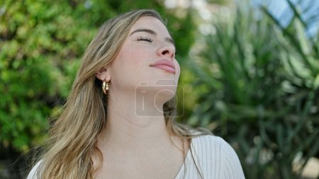 Photo for Young blonde woman breathing with closed eyes at park - Royalty Free Image