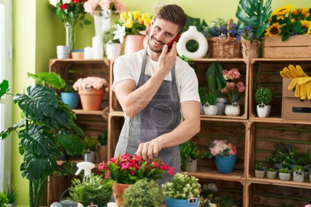 Téléchargez les photos : Jeune caucasien homme fleuriste parler sur smartphone usine de découpe à la boutique de fleurs - en image libre de droit