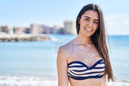 Foto de Joven mujer hispana sonriendo confiada vistiendo bikini en la playa - Imagen libre de derechos
