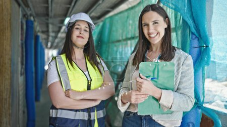 Photo for Two women architect and worker holding clipboard working at street - Royalty Free Image