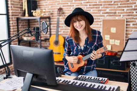 Photo for Young woman musician singing song playing ukelele at music studio - Royalty Free Image