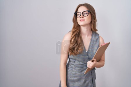 Photo for Caucasian woman wearing glasses and business clothes looking away to side with smile on face, natural expression. laughing confident. - Royalty Free Image