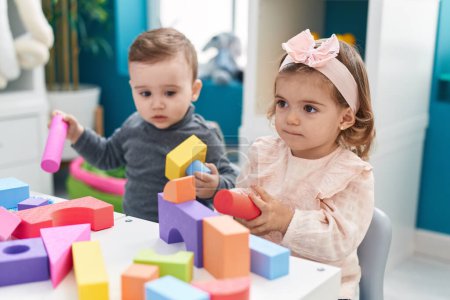 Photo for Adorable boy and girl playing with construction blocks sitting on table at kindergarten - Royalty Free Image