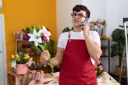 Téléchargez les photos : Non binary man florist talking on smartphone holding flowers at flower shop - en image libre de droit