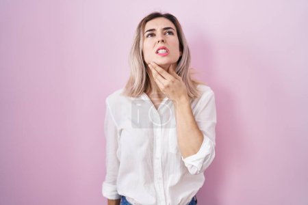 Photo for Young beautiful woman standing over pink background touching painful neck, sore throat for flu, clod and infection - Royalty Free Image