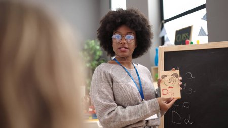 Téléchargez les photos : Femme afro-américaine enseignante préscolaire ayant des leçons de vocabulaire à la maternelle - en image libre de droit