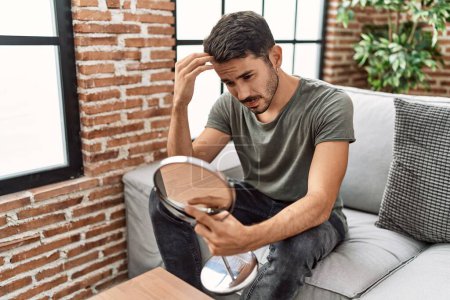 Téléchargez les photos : Young hispanic man lookin hair on mirror at home - en image libre de droit