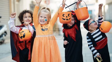 Téléchargez les photos : Groupe d'enfants portant un costume d'Halloween tenant panier de citrouille à la rue - en image libre de droit