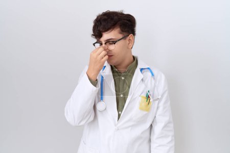 Photo for Young non binary man wearing doctor uniform and stethoscope tired rubbing nose and eyes feeling fatigue and headache. stress and frustration concept. - Royalty Free Image