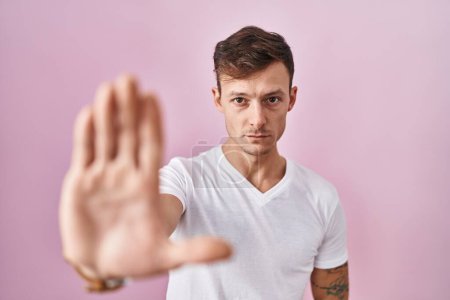 Photo for Caucasian man standing over pink background doing stop sing with palm of the hand. warning expression with negative and serious gesture on the face. - Royalty Free Image