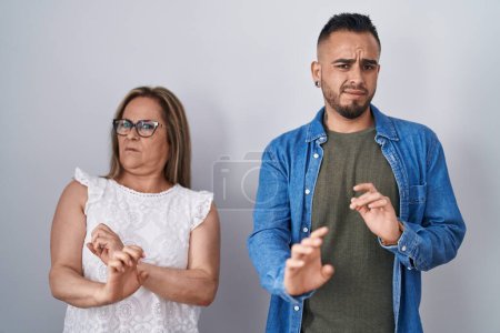 Photo for Hispanic mother and son standing together disgusted expression, displeased and fearful doing disgust face because aversion reaction. - Royalty Free Image