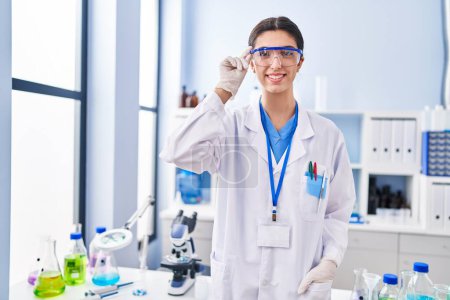Téléchargez les photos : Young beautiful hispanic woman scientist smiling confident standing at laboratory - en image libre de droit