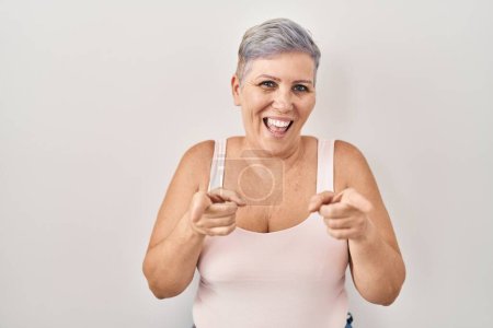 Téléchargez les photos : Middle age caucasian woman standing over white background pointing fingers to camera with happy and funny face. good energy and vibes. - en image libre de droit