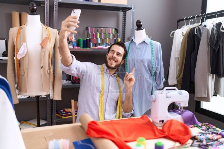 Photo for Young hispanic man tailor make selfie by smartphone at atelier - Royalty Free Image
