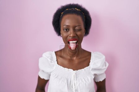 Photo for African woman with curly hair standing over pink background sticking tongue out happy with funny expression. emotion concept. - Royalty Free Image