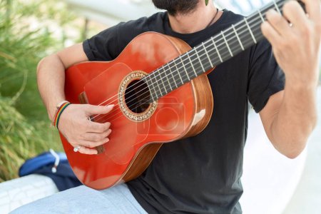 Photo for Young hispanic man musician playing classical guitar at park - Royalty Free Image