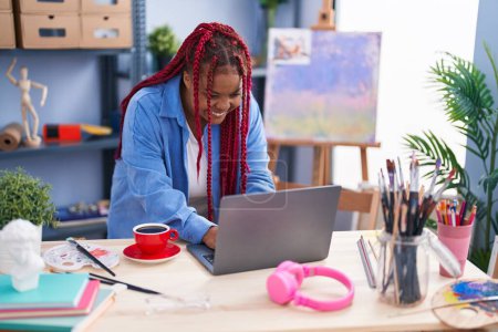 Téléchargez les photos : Artiste afro-américaine utilisant un ordinateur portable au studio d'art - en image libre de droit
