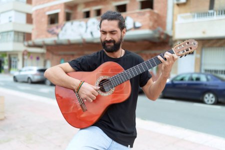Foto de Joven músico hispano tocando guitarra clásica en la calle - Imagen libre de derechos
