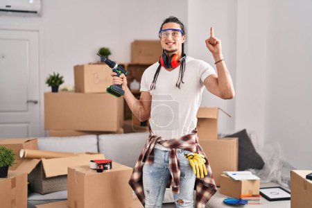 Photo for Hispanic man with long hair holding screwdriver at new home surprised with an idea or question pointing finger with happy face, number one - Royalty Free Image