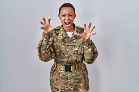 Photo for Beautiful african american woman wearing camouflage army uniform smiling funny doing claw gesture as cat, aggressive and sexy expression - Royalty Free Image