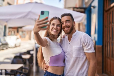 Foto de Hombre y mujer pareja sonriendo confiado hacer selfie por teléfono inteligente en la calle - Imagen libre de derechos