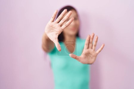 Téléchargez les photos : Jeune femme hispanique debout sur fond rose faisant cadre en utilisant les mains paumes et les doigts, perspective de la caméra - en image libre de droit