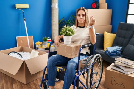 Foto de Mujer joven sentada en silla de ruedas mudándose a un nuevo hogar haciendo un gesto italiano con la mano y los dedos expresión de confianza - Imagen libre de derechos