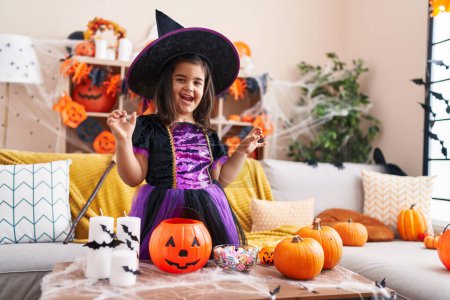Foto de Adorable chica hispana teniendo fiesta de Halloween haciendo gesto de miedo en casa - Imagen libre de derechos