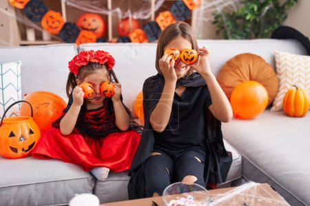 Foto de Adorable niño y niña con traje de halloween sosteniendo cestas de calabaza sobre los ojos en casa - Imagen libre de derechos