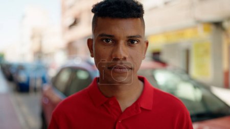 Téléchargez les photos : Young latin man with relaxed expression standing at street - en image libre de droit