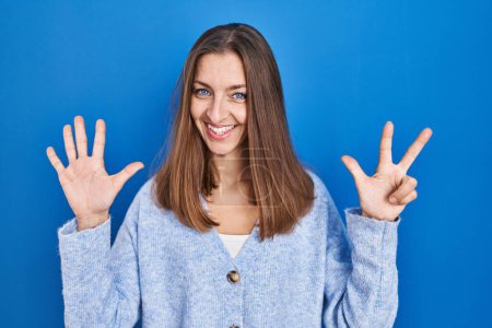 Photo for Young woman standing over blue background showing and pointing up with fingers number eight while smiling confident and happy. - Royalty Free Image