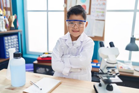 Photo for Adorable hispanic boy student smiling confident standing with arms crossed gesture at laboratory classroom - Royalty Free Image