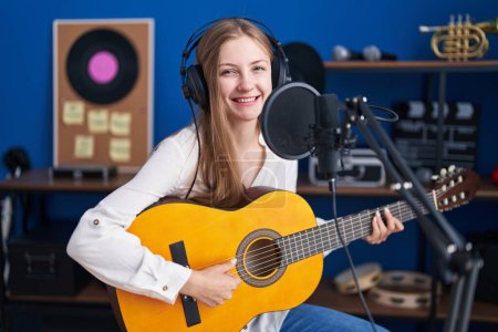 Foto de Young caucasian woman musician singing song playing classical guitar at music studio - Imagen libre de derechos
