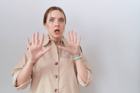 Photo for Young caucasian woman wearing casual shirt afraid and terrified with fear expression stop gesture with hands, shouting in shock. panic concept. - Royalty Free Image