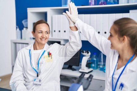 Téléchargez les photos : Two women scientists high five with hands raised up at laboratory - en image libre de droit