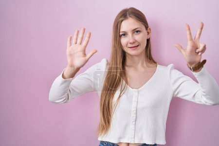Photo for Young caucasian woman standing over pink background showing and pointing up with fingers number eight while smiling confident and happy. - Royalty Free Image
