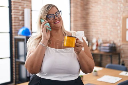 Foto de Trabajadora de negocios joven hablando en smartphone tomando café en la oficina - Imagen libre de derechos