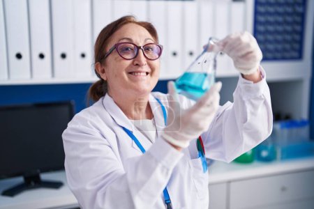 Foto de Mujer científica sonriendo confiada midiendo líquido en el laboratorio - Imagen libre de derechos