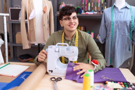 Téléchargez les photos : Non binary man tailor smiling confident using sewing machine at atelier - en image libre de droit