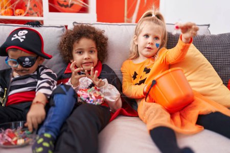 Photo for Group of kids wearing halloween costume eating candies at home - Royalty Free Image