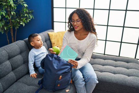 Photo for Mother and son prepare school backpack sitting on sofa at home - Royalty Free Image