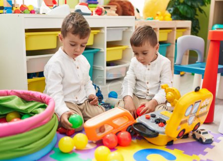 Téléchargez les photos : Adorables garçons assis sur le sol jouant avec des jouets de voiture à la maternelle - en image libre de droit