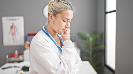 Foto de Joven hermosa mujer hispana doctora de pie con expresión de duda pensando en la clínica - Imagen libre de derechos
