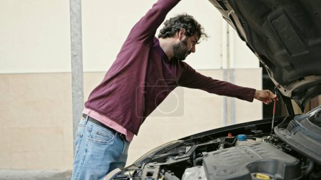 Photo for Young hispanic man repairing motor car at street - Royalty Free Image