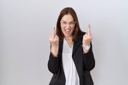 Foto de Beautiful brunette woman wearing business jacket and glasses showing middle finger doing fuck you bad expression, provocation and rude attitude. screaming excited - Imagen libre de derechos
