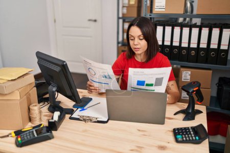 Foto de Young beautiful hispanic woman ecommerce business worker using laptop reading document at office - Imagen libre de derechos