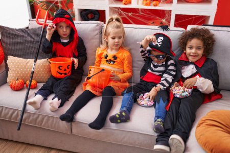 Foto de Grupo de niños con disfraz de Halloween sentados en el sofá en casa - Imagen libre de derechos