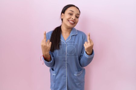 Foto de Young arab woman wearing blue pajama showing middle finger doing fuck you bad expression, provocation and rude attitude. screaming excited - Imagen libre de derechos