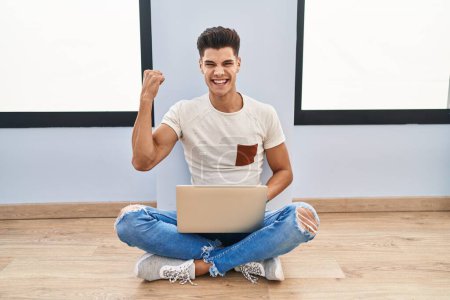 Photo for Young hispanic man using laptop at home very happy and excited doing winner gesture with arms raised, smiling and screaming for success. celebration concept. - Royalty Free Image